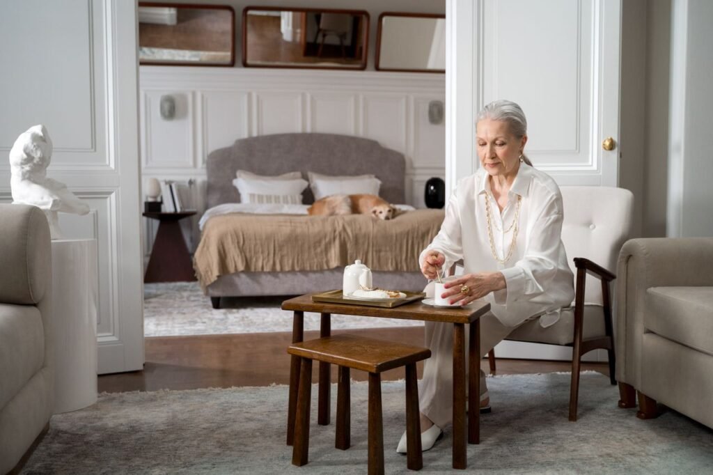 Simple Daily Habits for Better Health and Wellbeing Serene elderly woman in a stylish living room setting enjoying tea, embodying elegance and comfort.