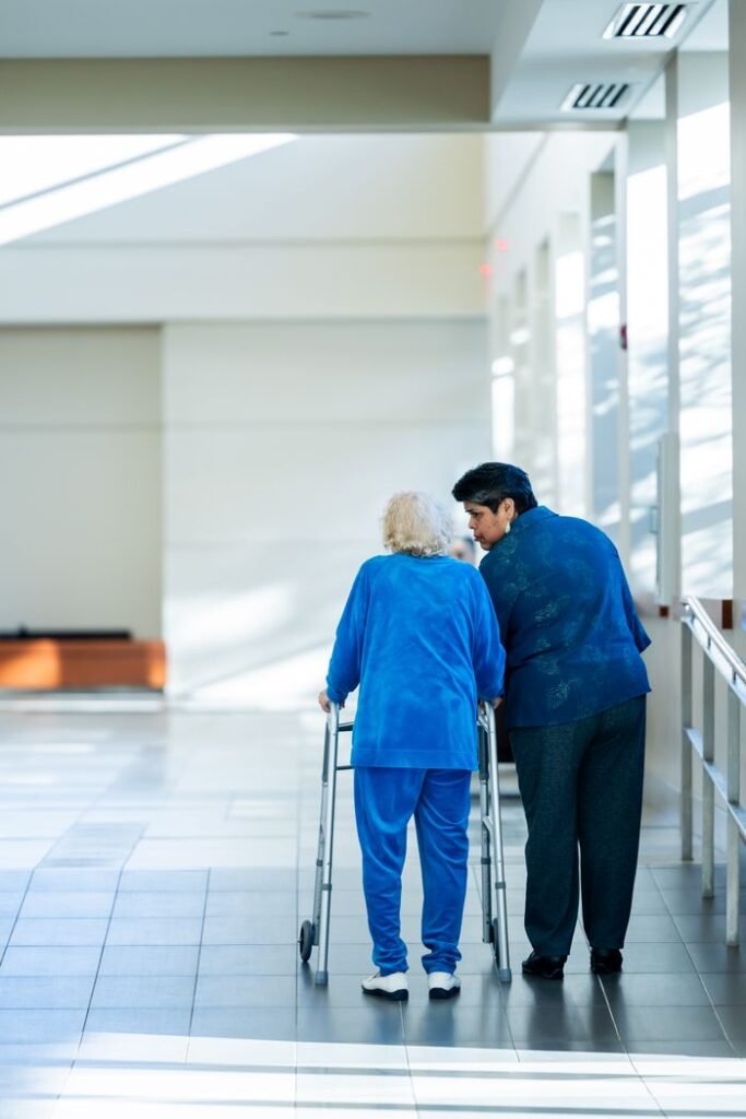 The Orchid View Care Home Case: Neglect, Missed Warnings and Lessons A nurse assists an elderly woman with a walker in a bright hospital corridor.