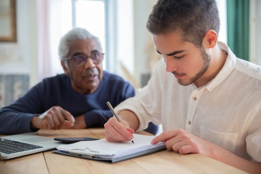 A care worker recording accurate care notes beside an older man